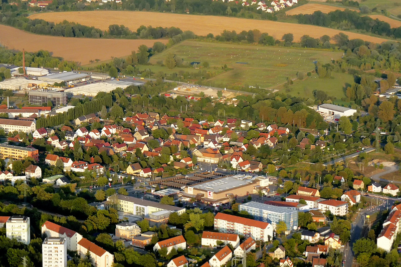 Der Ortsteil Löbstedt mit Wohnhäuser, dem Supermarkt Kaufland, Wiesen und Feldern im Hintergrund.