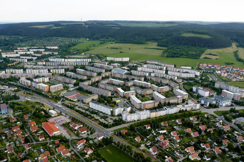 Der Ortsteil Winzerla mit Wohnhäusern, einem Fußballfeld, diversen Supermärkten, Wiesen und Wald.