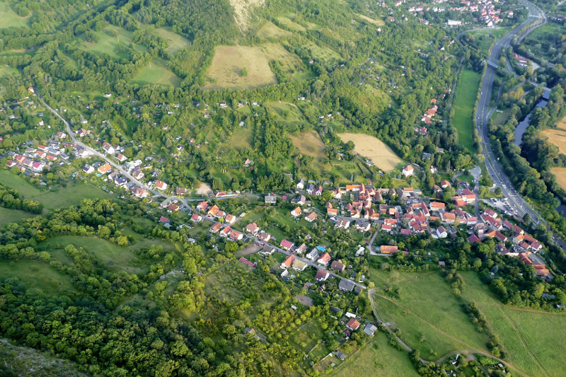 Der Ortsteil Wöllnitz an der Bundesstraße 88 mit Wohnhäusern, Wiesen und Wald.