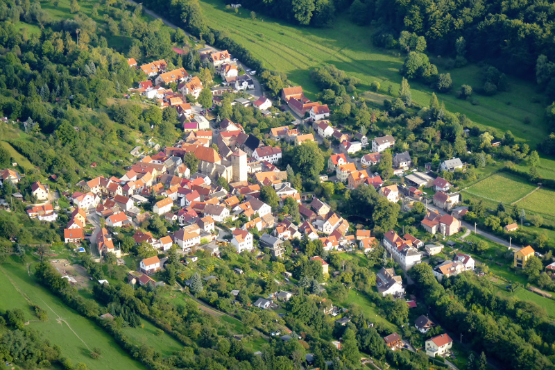 Der Ortsteil Ziegenhain mit Wohnhäusern, einer Kirche, Wiesen und Wald.