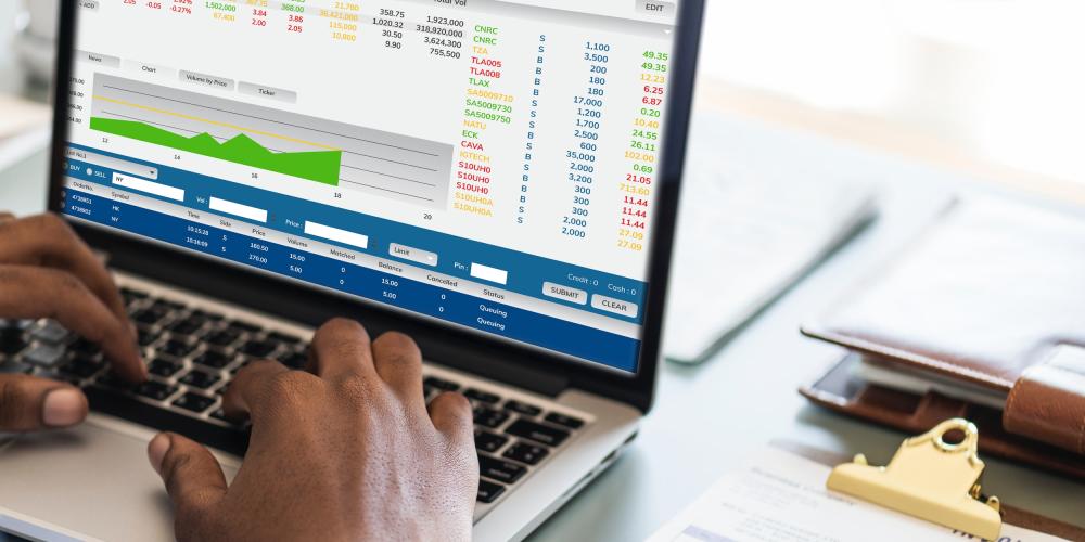 Laptop mit statistischen Grafiken auf einem Schreibtisch, ein Mann schreibt auf der Tastatur